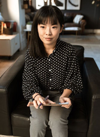 Female hiring manager on a black sofa chair with a clipboard taking notes.